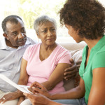 Senior Couple Talking To Financial Advisor At Home